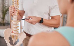 A chiropractor gently adjusts a woman's lower back in a comfortable, light-filled clinic.