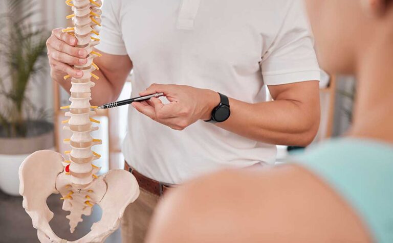A chiropractor gently adjusts a woman's lower back in a comfortable, light-filled clinic.