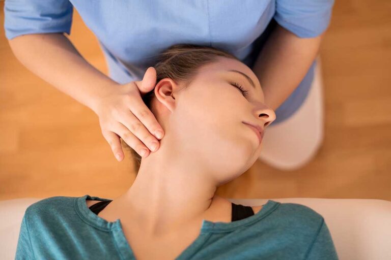 A person receives focused back massage while a clinician discusses spinal movement beside a treatment table.